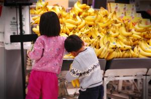 Two children choosing bananas at a store